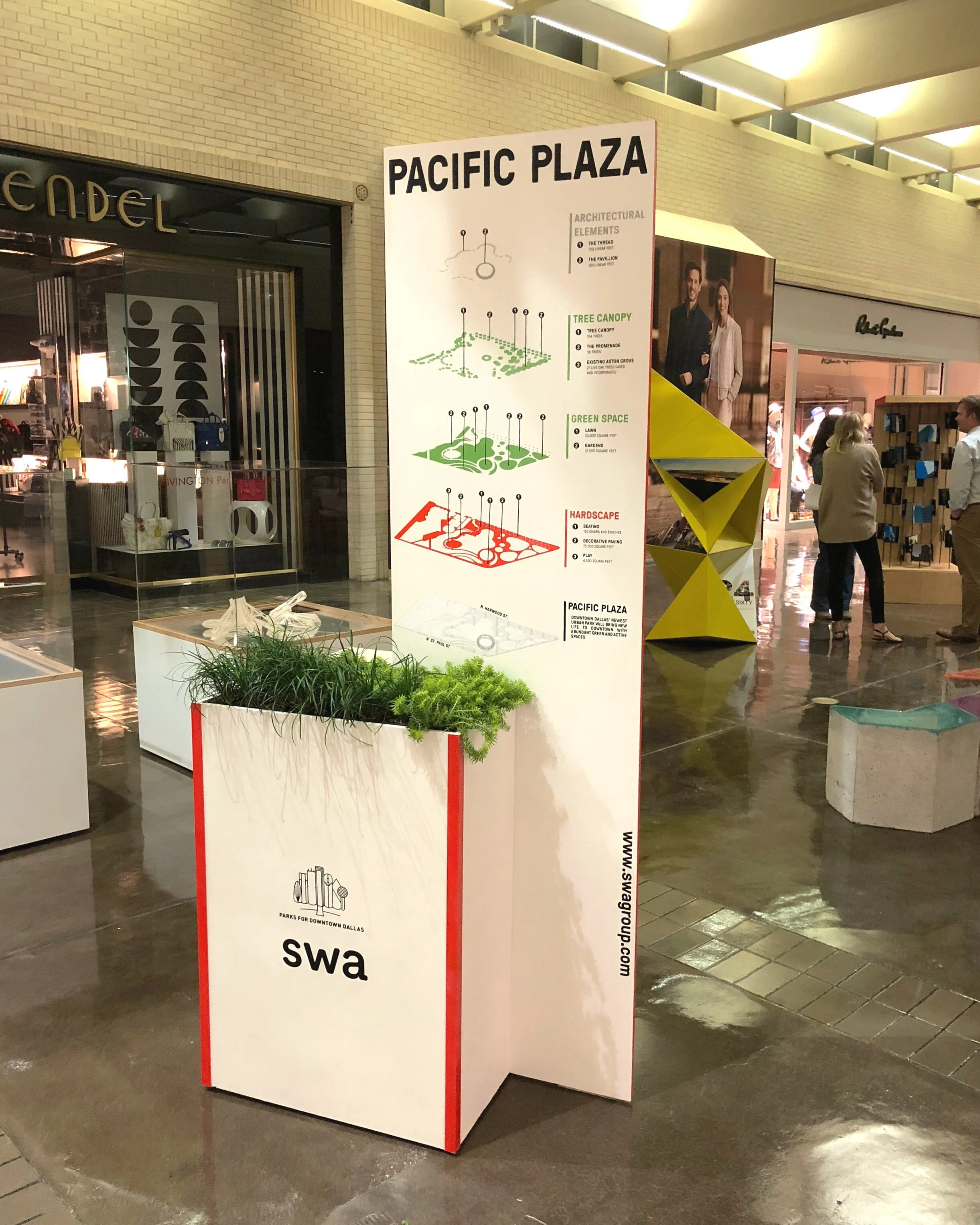 The display at NorthPark, front: the park’s layers on a tall white panel with red edges, rising from a planter marked SWA and Parks for Downtown Dallas