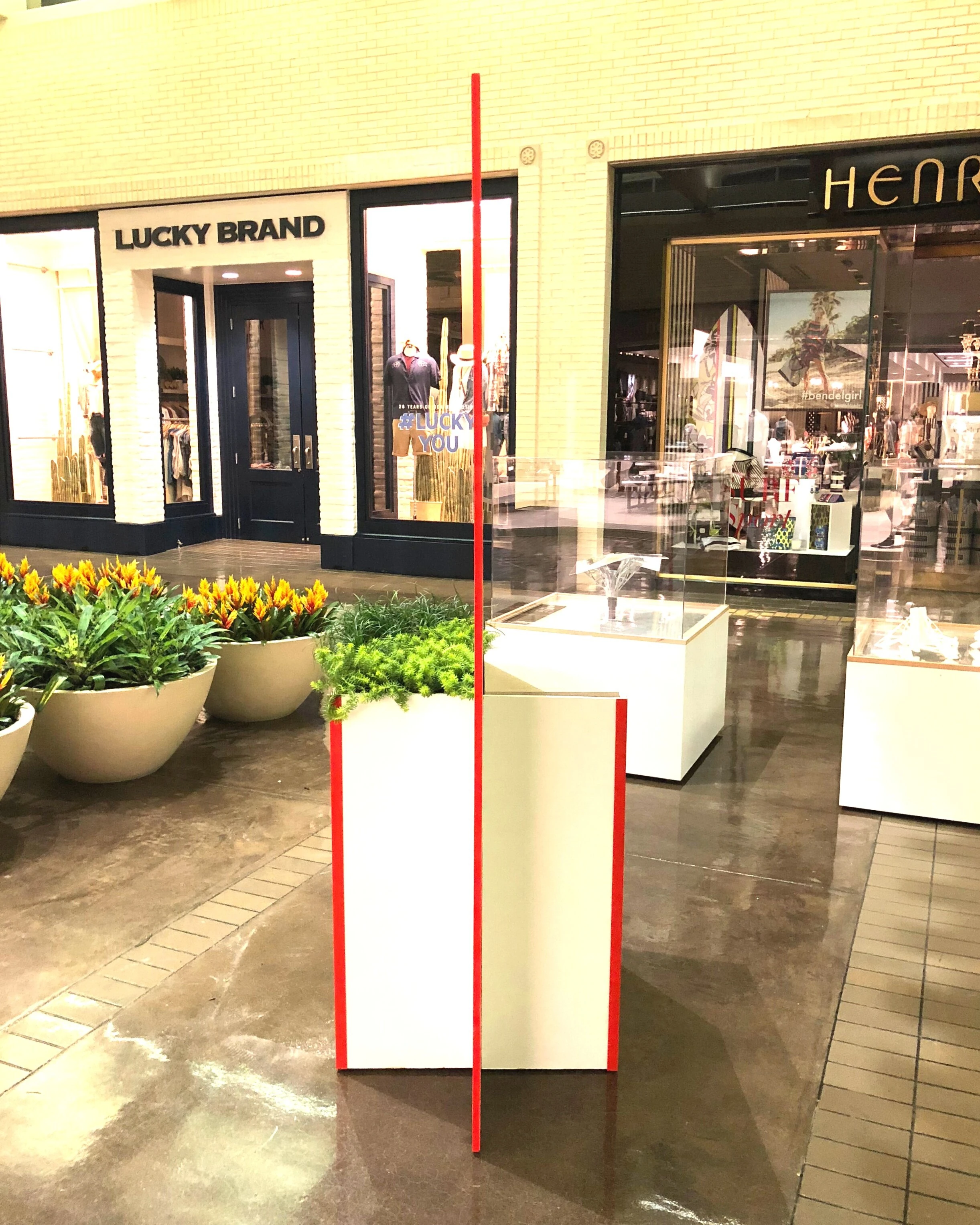 The display edge on: the thin red-edged panel standing in its planter in the mall